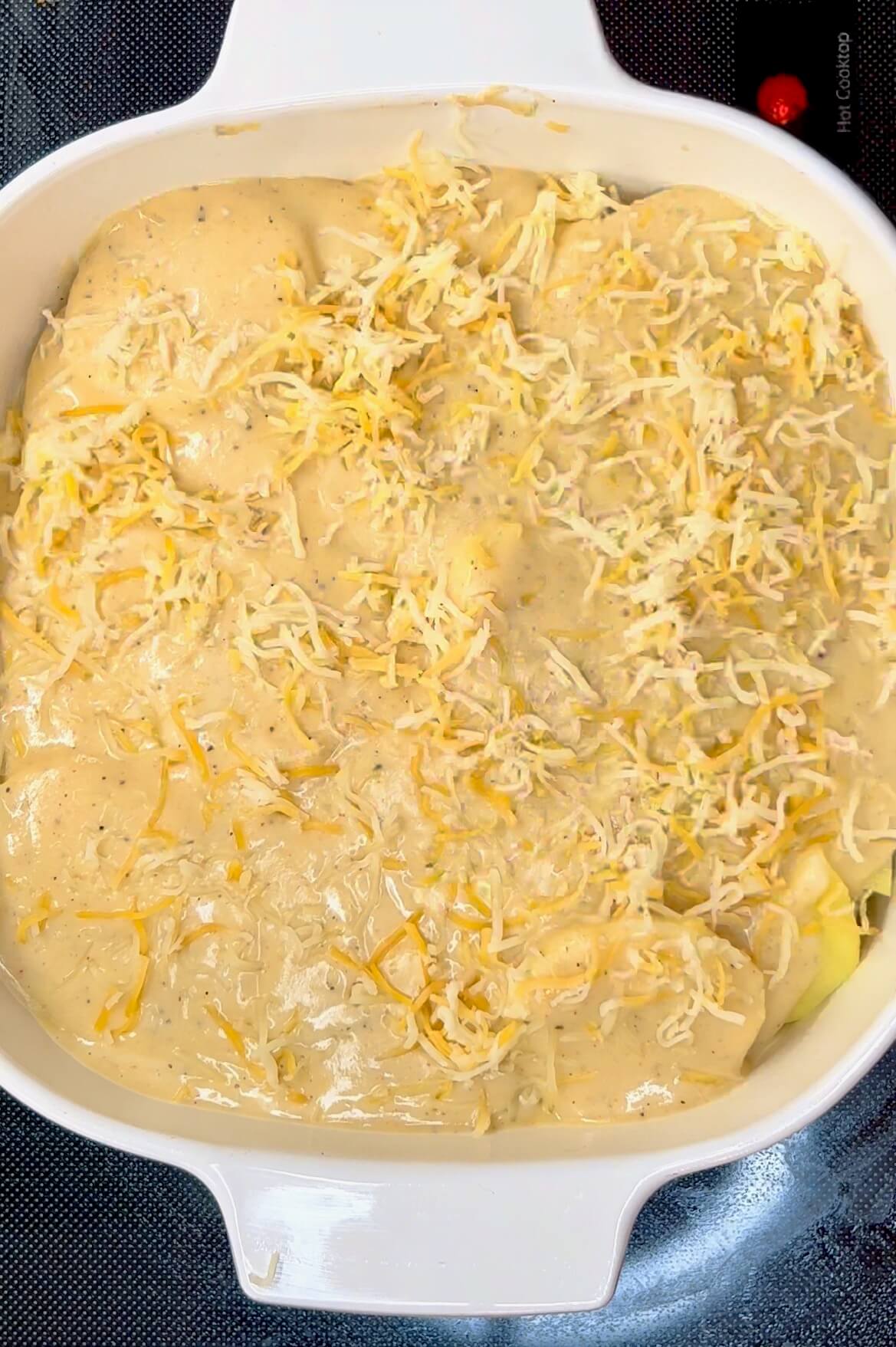 Cover the last layer of sliced potatoes with cheese sauce, then top with cheese.